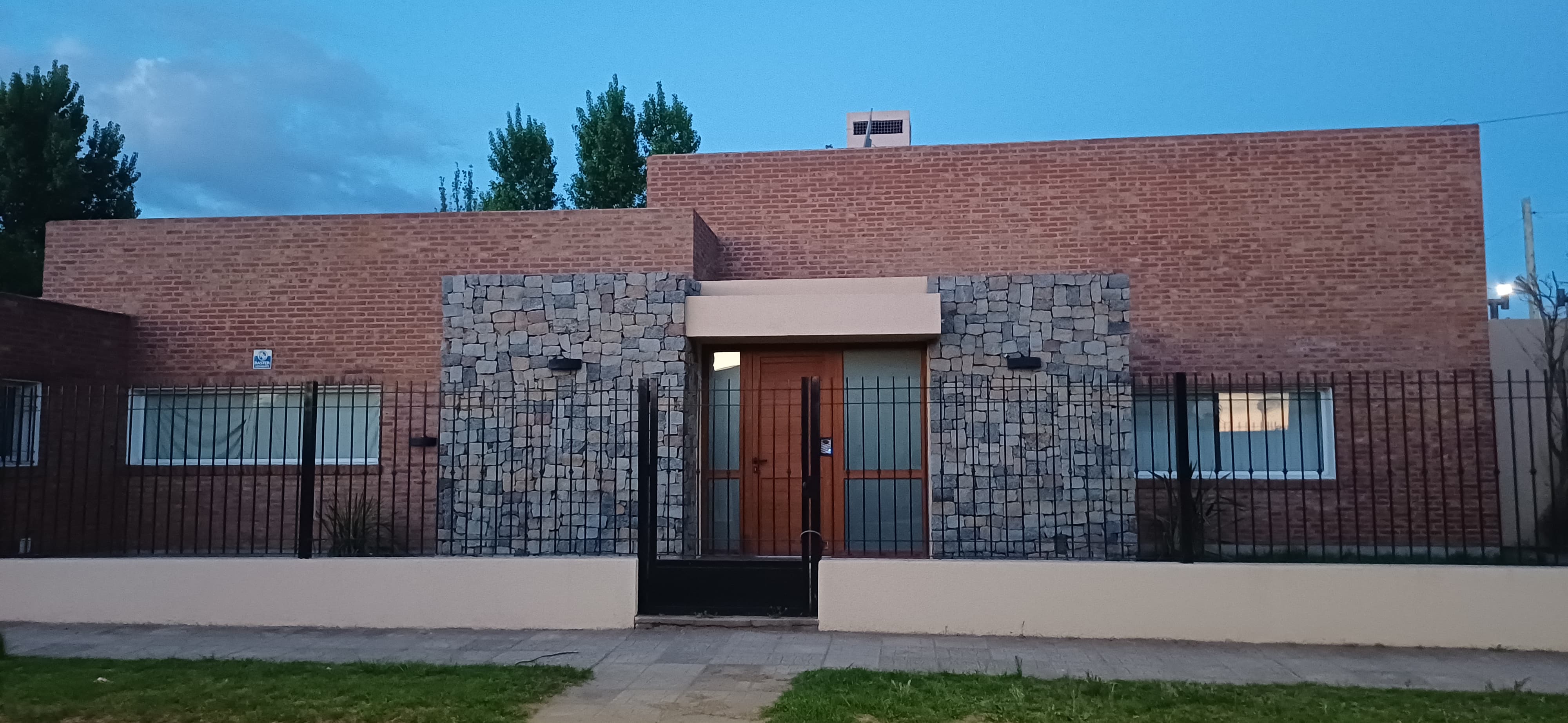 Casa de ladrillo visto con frente de piedra y puerta de madera